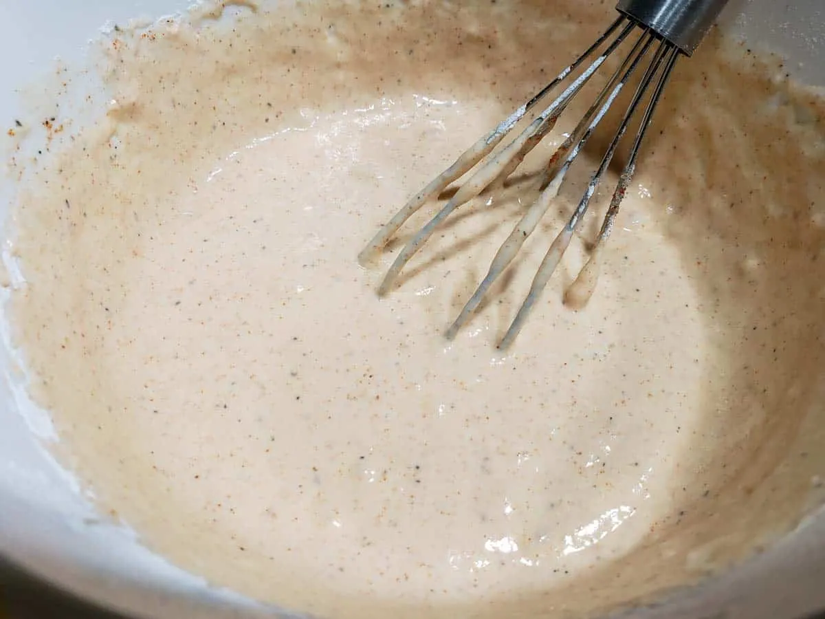 a bowl filled with light orange beer batter and a whisk