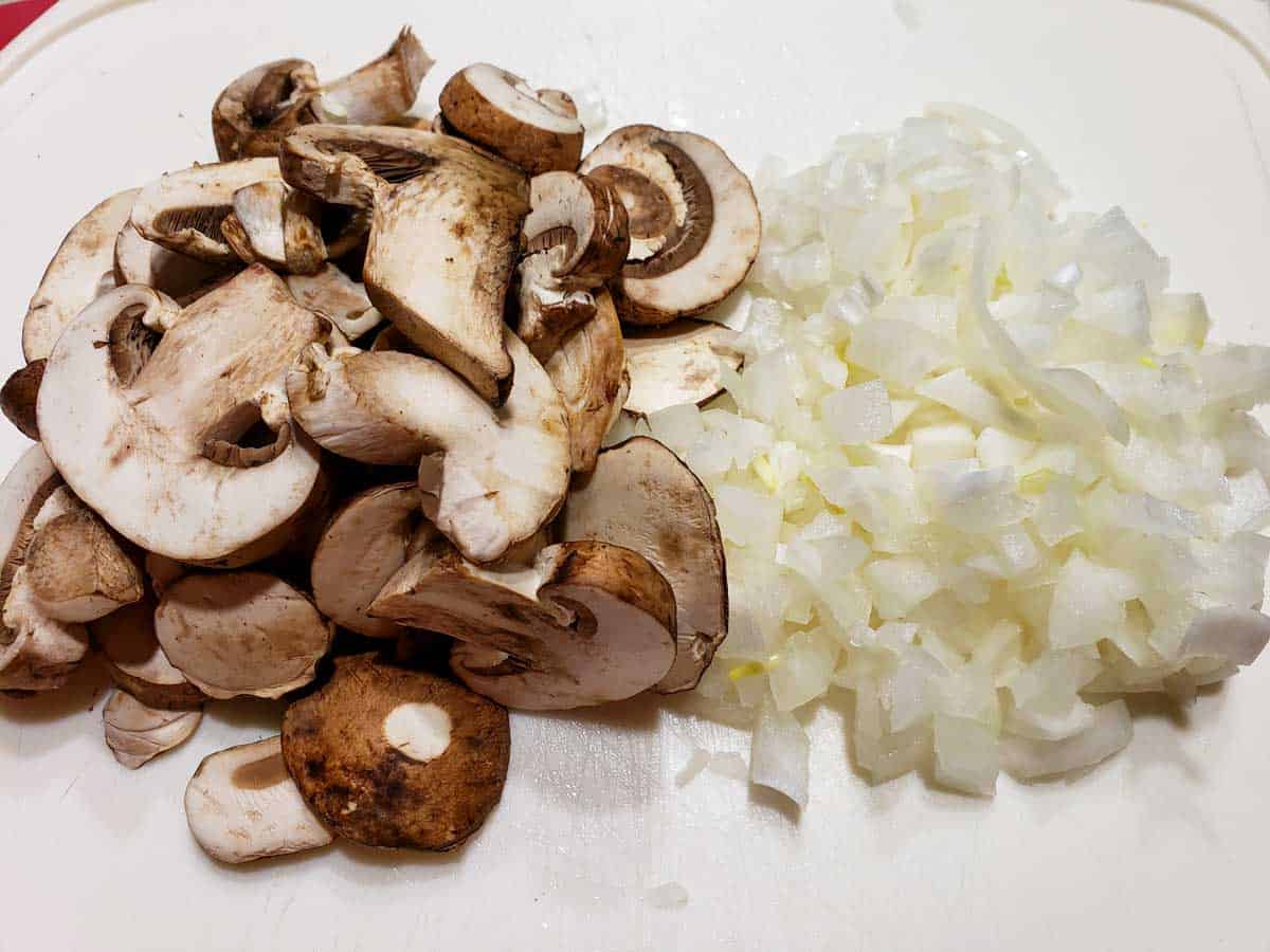 sliced mushrooms and dice onions on a cutting board