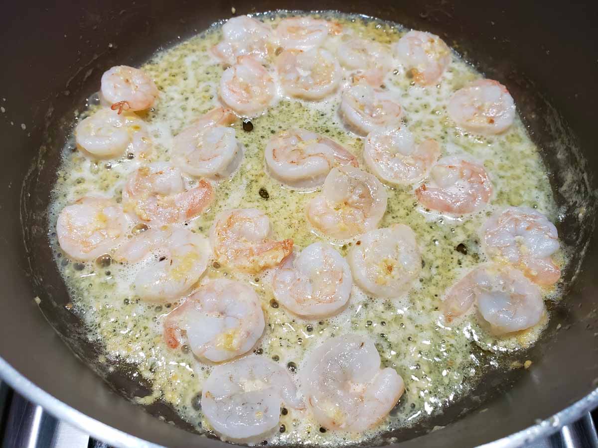 pink shrimp cooking in a yellow butter sauce