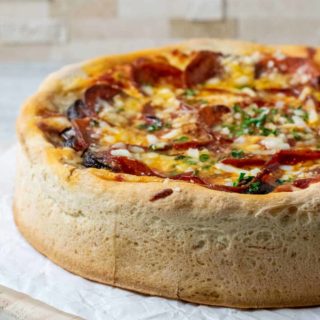 a pizza with thick and tall crust on parchment paper