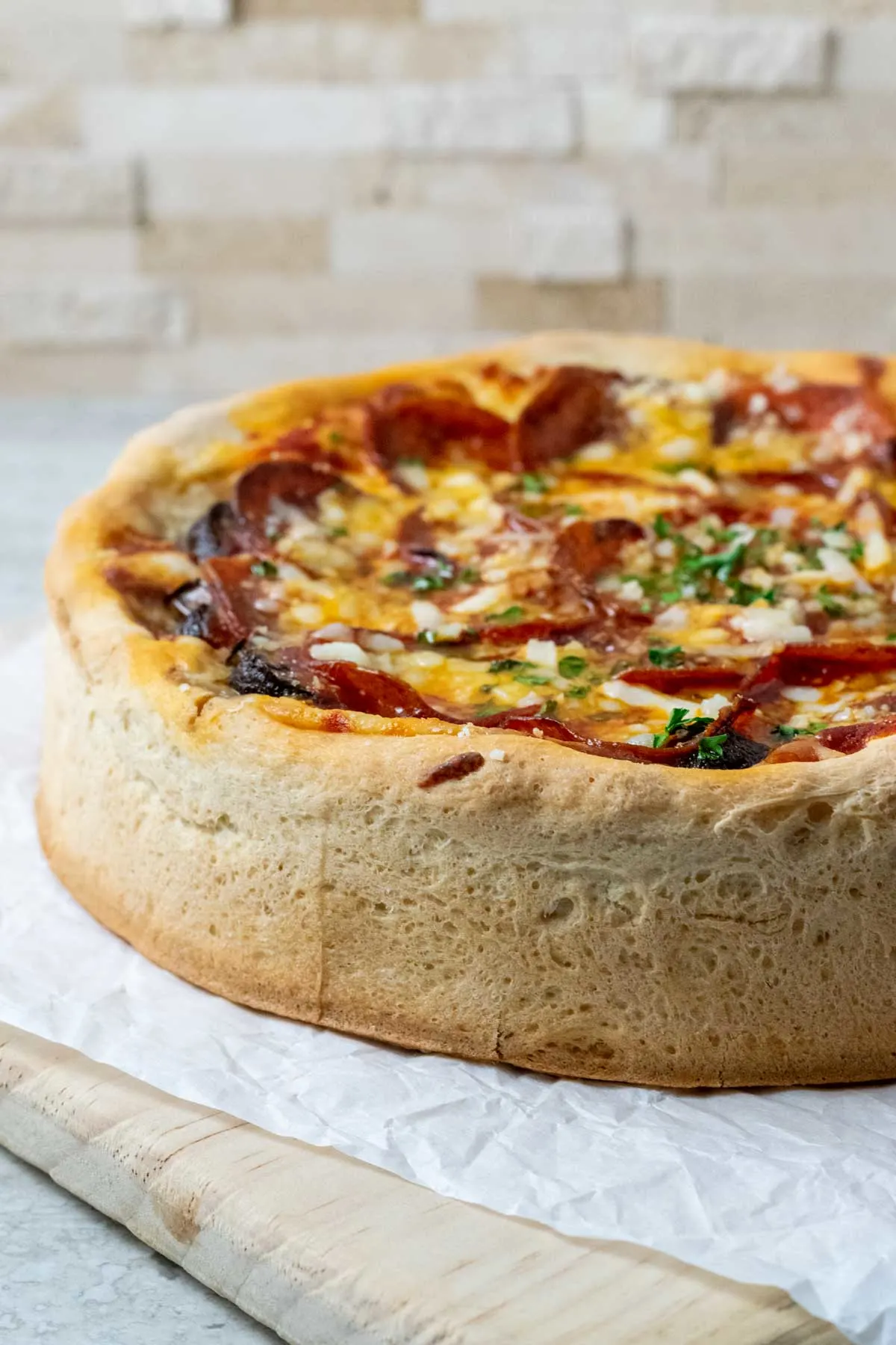 a pizza with thick and tall crust on parchment paper