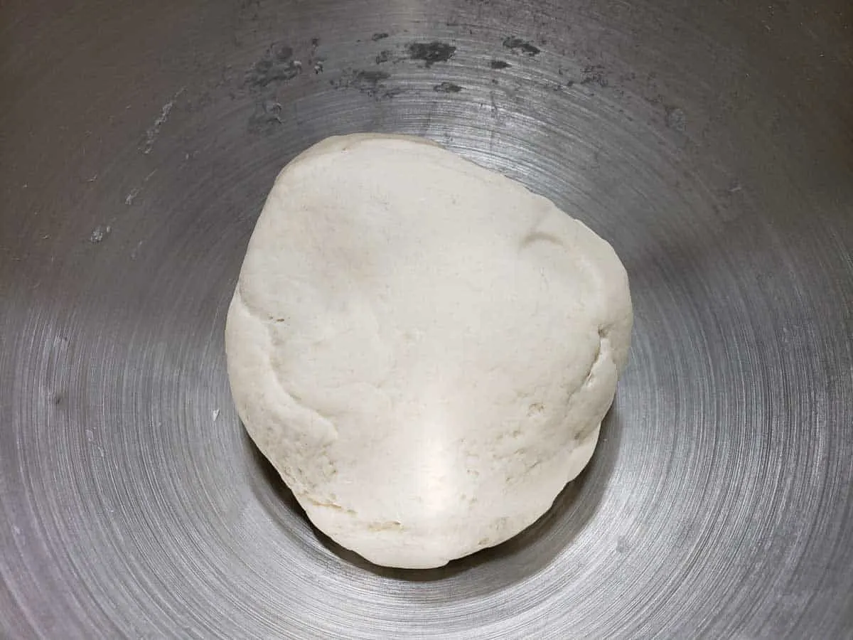 a ball of pizza dough in a silver bowl.