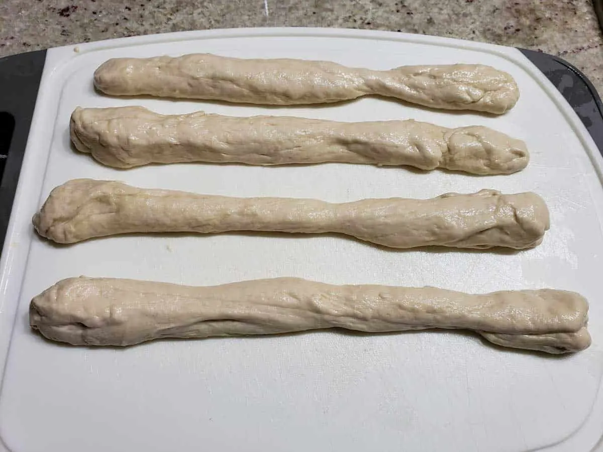 4 pretzel dough rods on a cutting board
