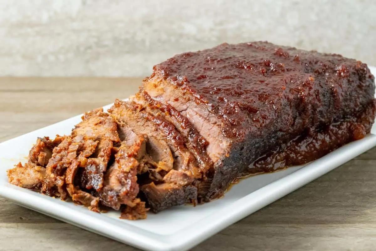 a crock pot Beef brisket with BBQ Sauce half sliced on a plate