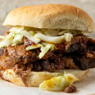 a bun filled with thin sliced bbq beef brisket topped with creamy coleslaw