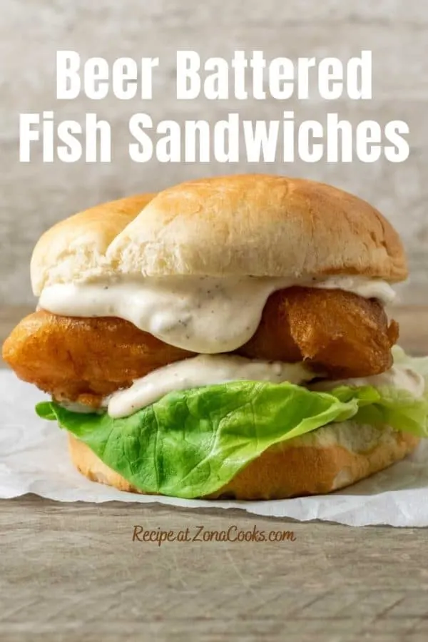 a bun filled with lettuce, white creamy sauce, and golden brown fish filet and text saying Beer Battered Fish Sandwiches Recipe at ZonaCooks.com.