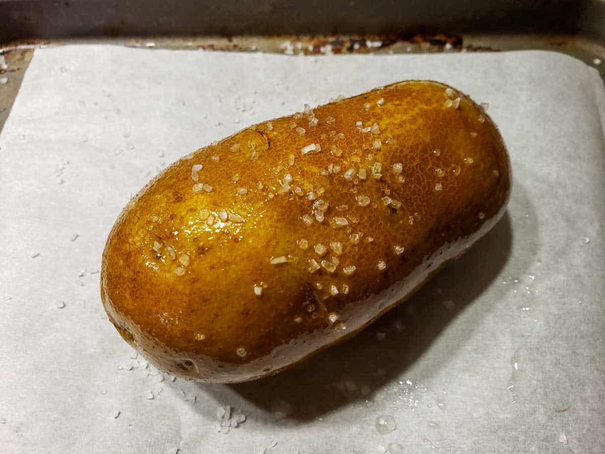 a brown potato coated in oil and course sea salt
