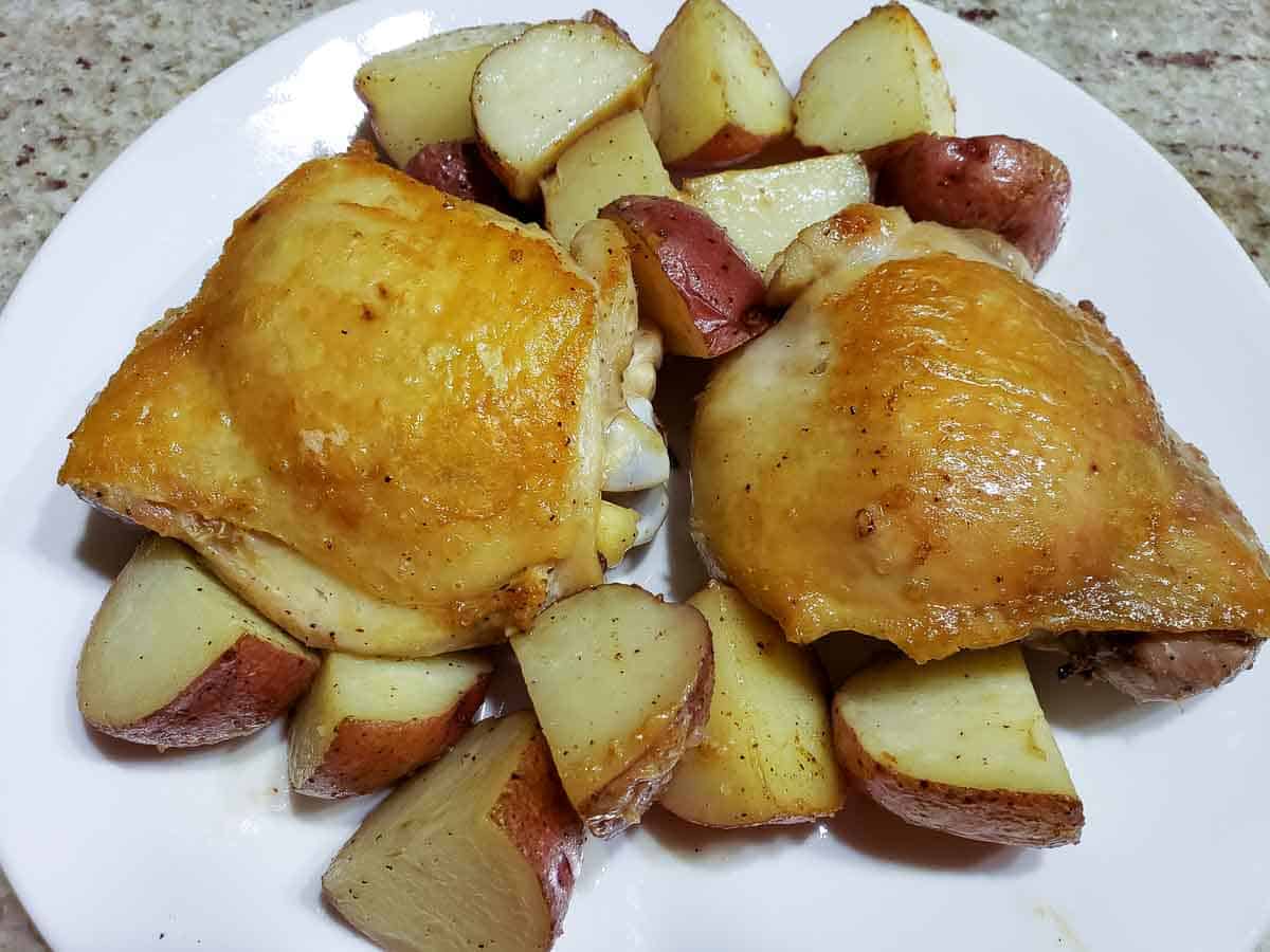 two browned chicken thighs red potatoes on a plate