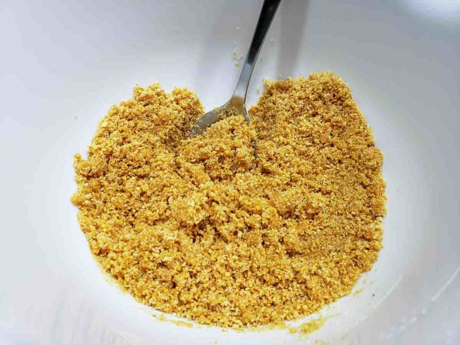 a bowl filled with graham crumbs mixed with melted butter.