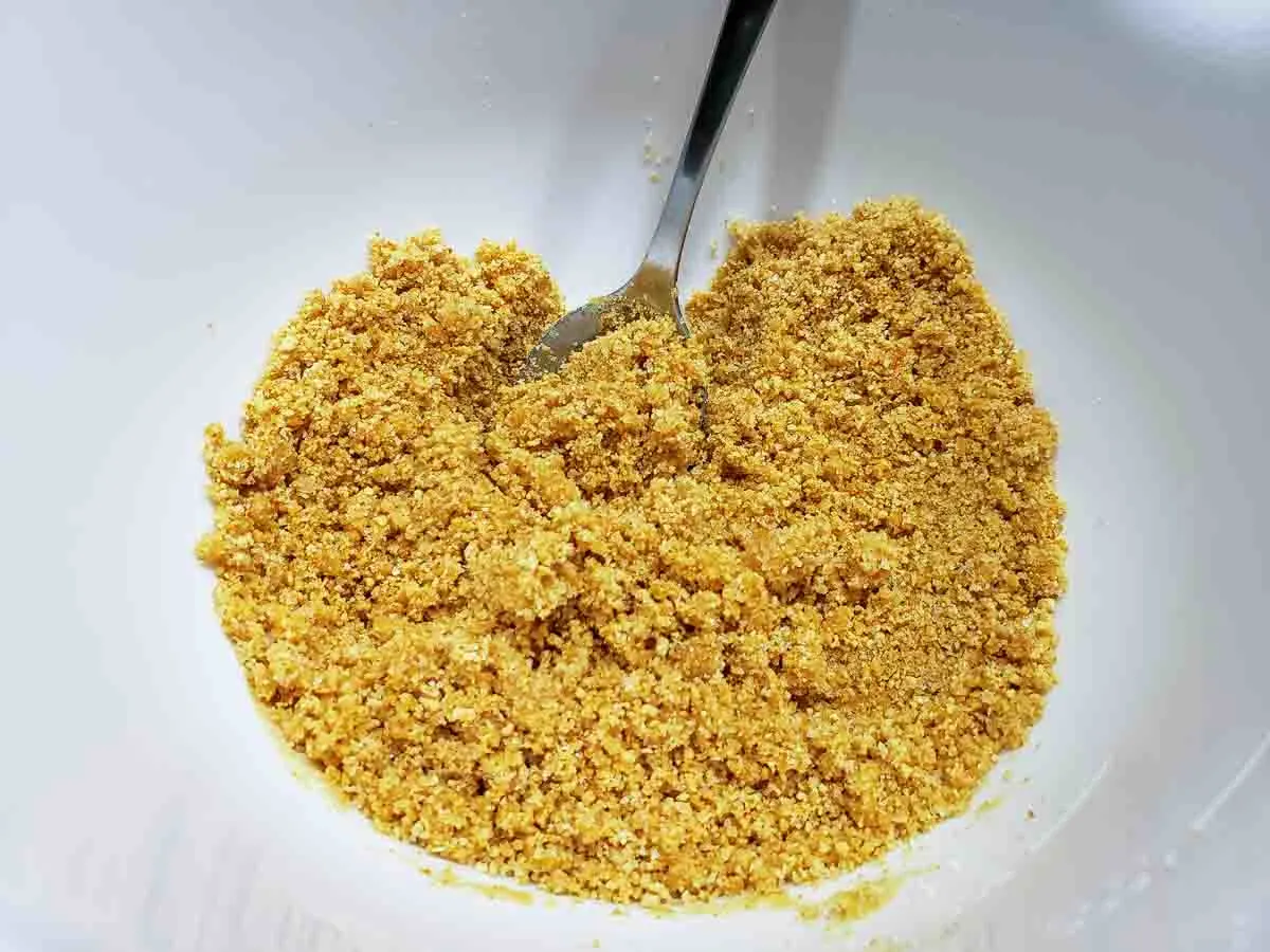 a bowl filled with graham crumbs mixed with melted butter