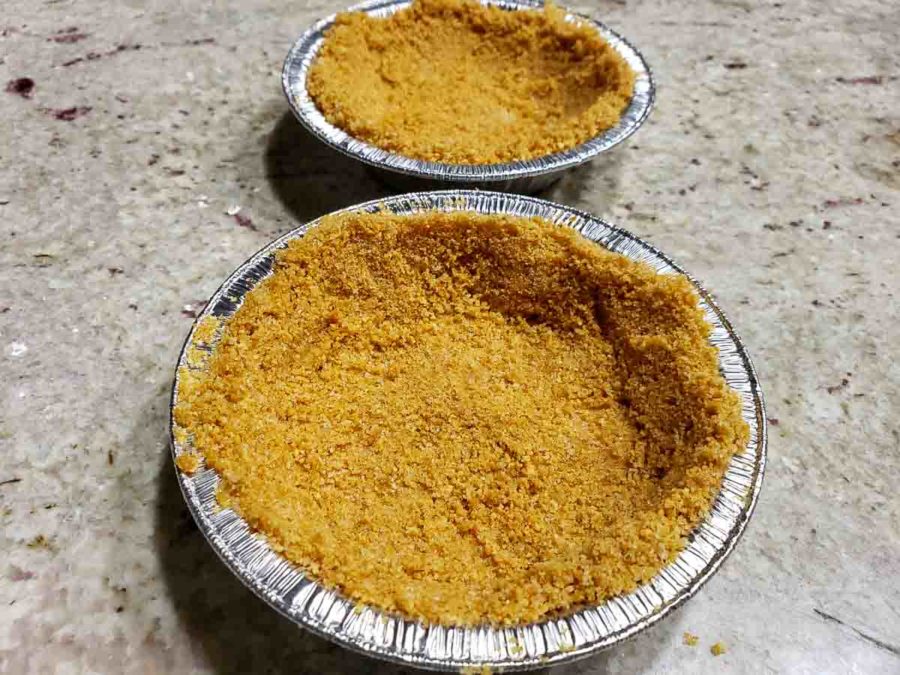 two small pie tins filled with graham crust mixture.