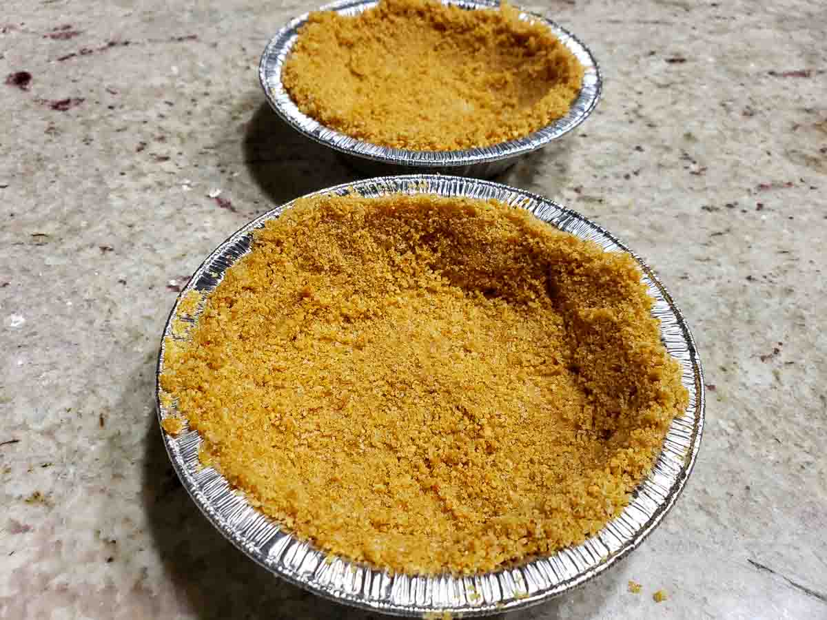 two small pie tins filled with graham crust mixture