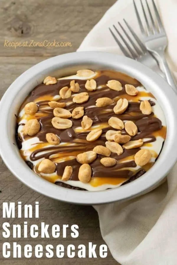 a small pie pan filled with chocolate crust, creamy filling, caramel sauce drizzle, chocolate ganache drizzle, and peanuts.