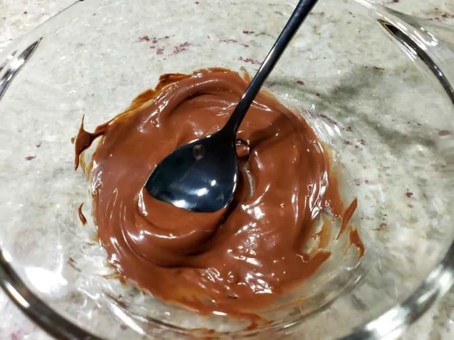 chocolate ganache sauce mixed in a bowl with a spoon.