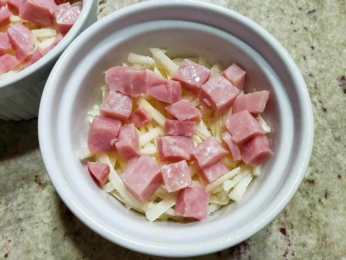 diced ham on top of shredded hash browns in a casserole dish