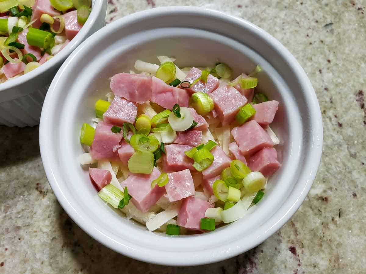 shredded hash browns, diced ham, and green onions in a ramekin