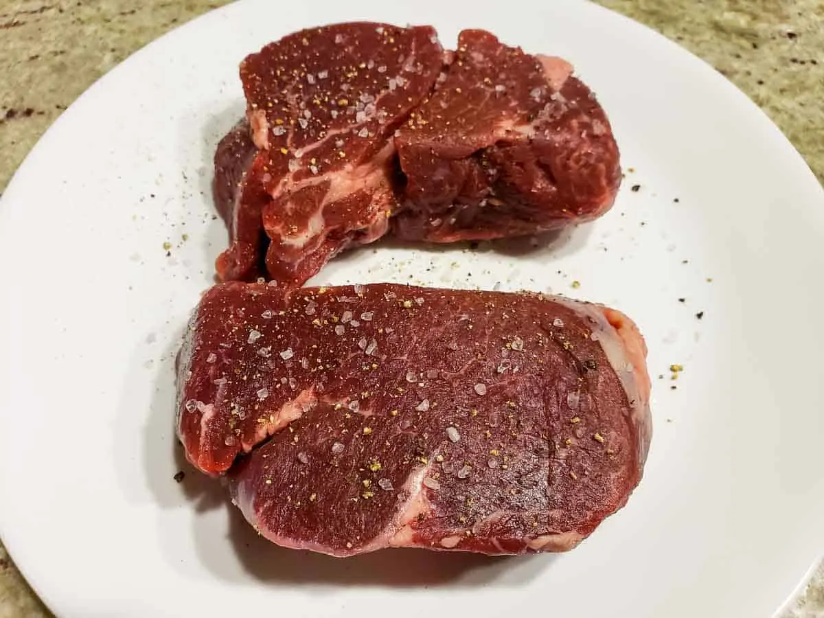 two filet mignon beef tenderloin steaks sprinkled with salt and pepper