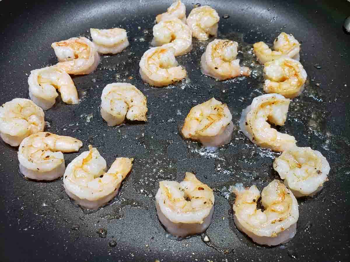 a frying pan filled with shrimp cooking in oil.