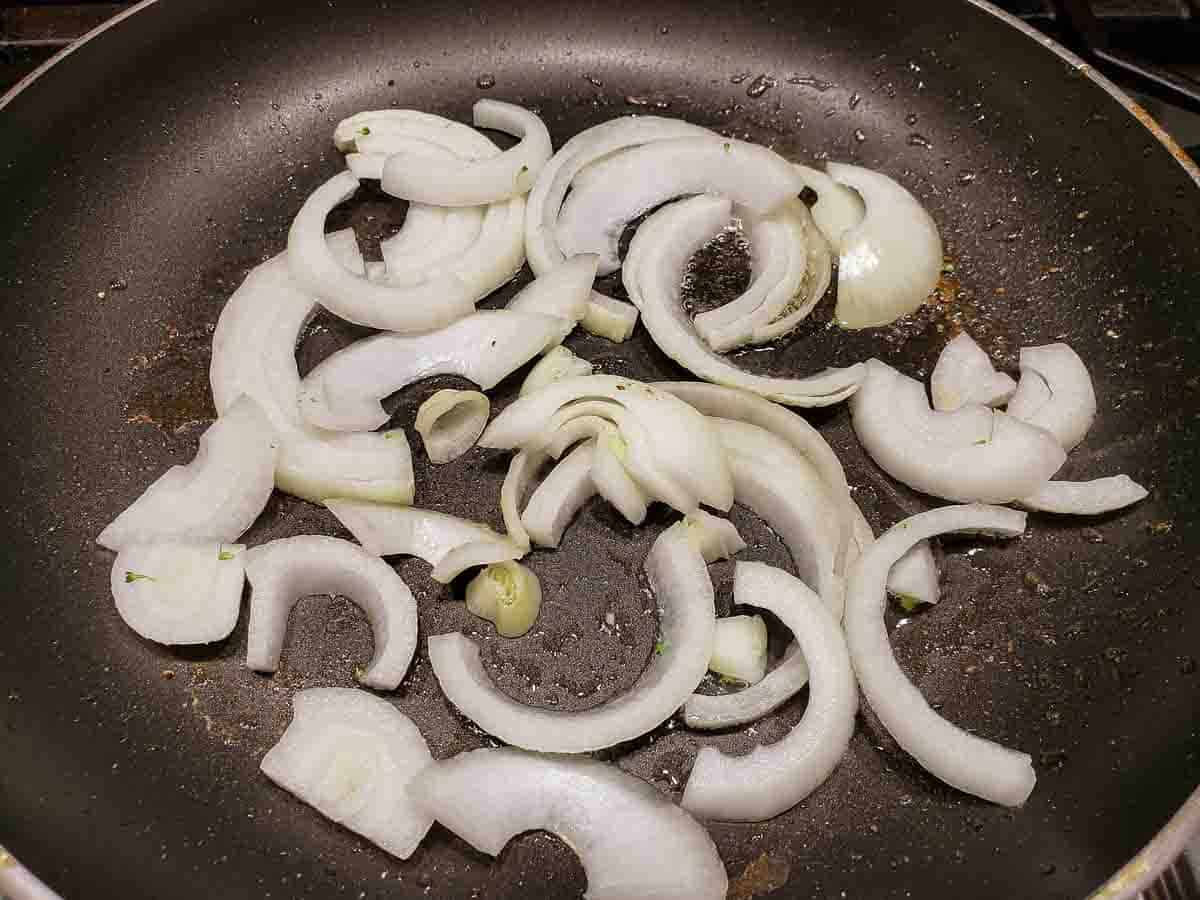 sliced onions cooking in a frying pan.