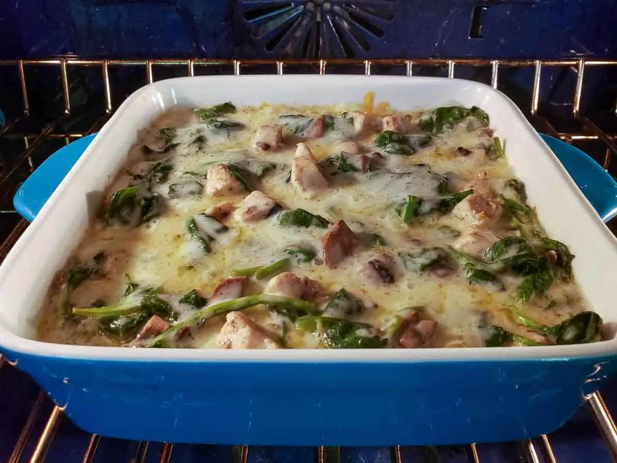 white lasagna with spinach and chicken baking in an oven