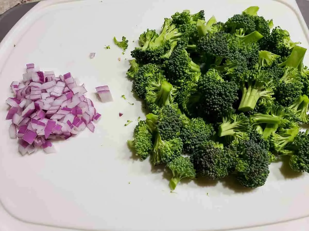 broccoli florets and diced red onions on a cutting board