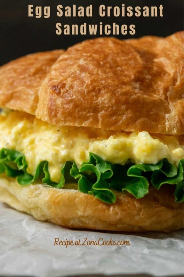 a large croissant filled with lettuce and creamy yellow chopped egg salad mixture and text reading egg salad croissant sandwiches recipe at zonacooks.com