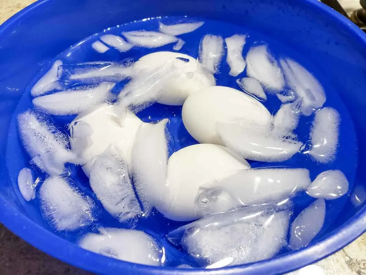 4 eggs cooling down in an ice water bath in a bowl