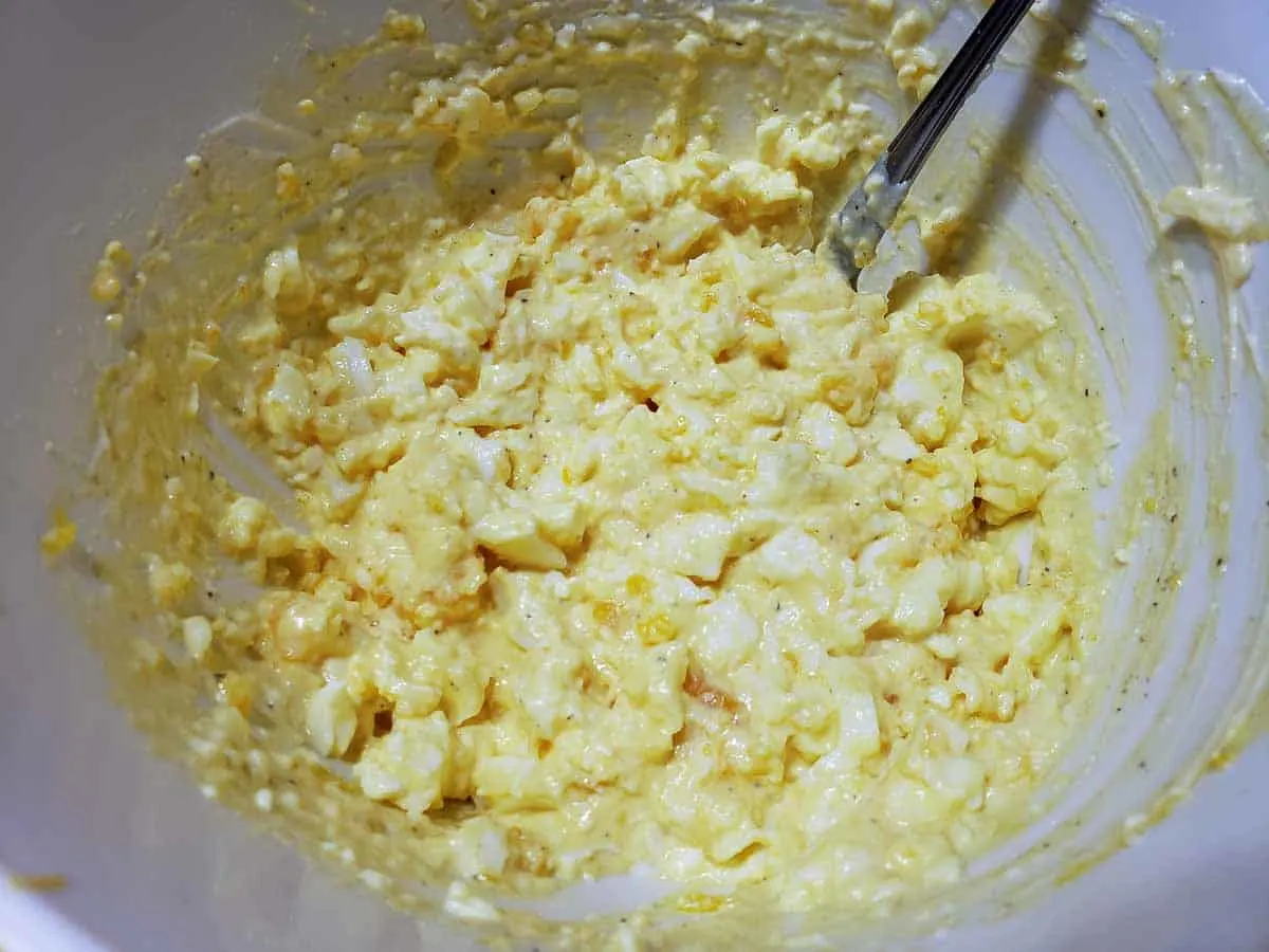 a bowl filled with creamy yellow egg salad mixed together