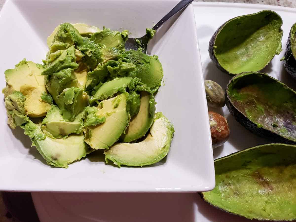 avocado scooped out of its skins and placed in a bowl