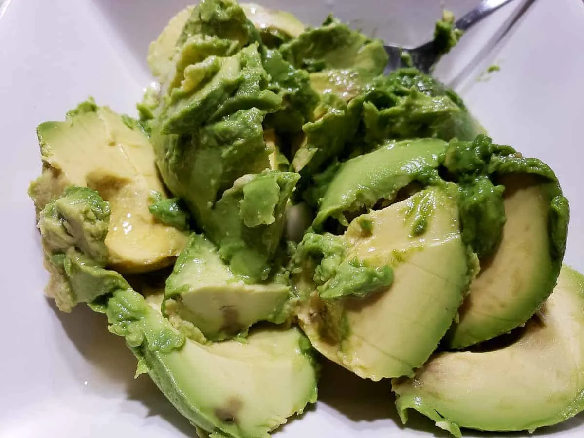 avocado slices mixed with lime juice and lemon juice in a bowl