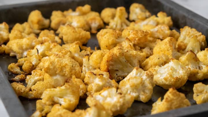a small baking sheet pan filled with golden brown oven baked cauliflower florets
