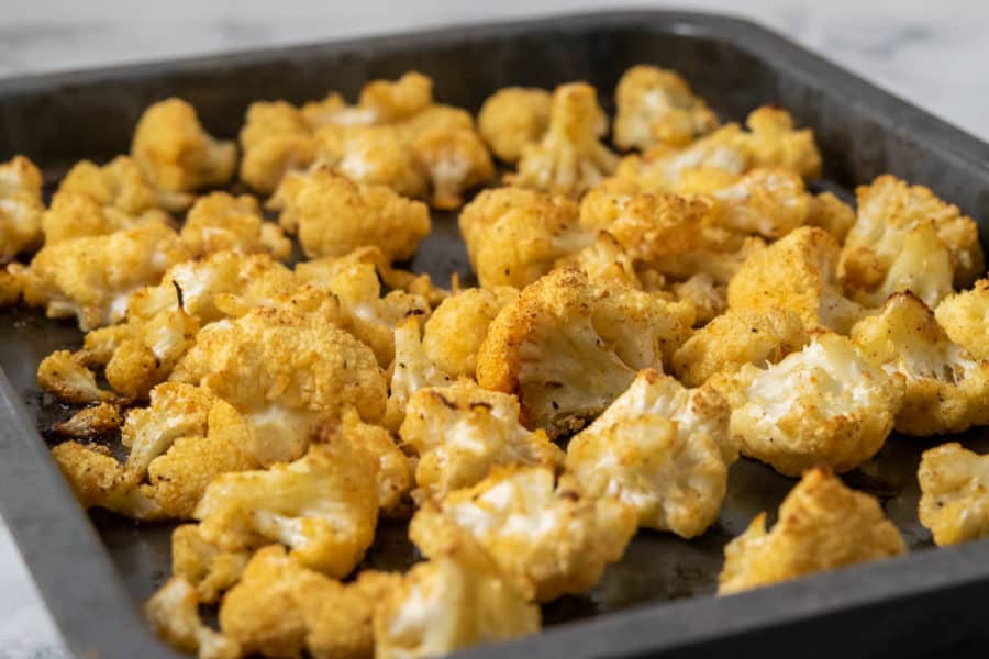 a small baking sheet pan filled with golden brown oven baked cauliflower florets