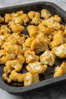 a small baking sheet pan filled with golden brown oven baked cauliflower florets