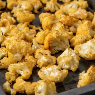 a small baking sheet pan filled with golden brown oven baked cauliflower florets