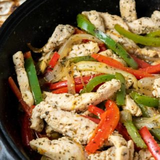 fire roasted tortillas and a cast iron skillet filled with sliced green pepper, red pepper, onions, and chicken in homemade fajita seasoning