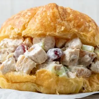 Chicken Salad Croissant with boneless chicken, grapes, almonds, and celery coated in a mayo dressing piled in a large buttery croissant roll.