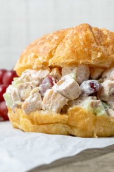 Chicken Salad Croissant with boneless chicken, grapes, almonds, and celery coated in a mayo dressing piled in a large buttery croissant roll.
