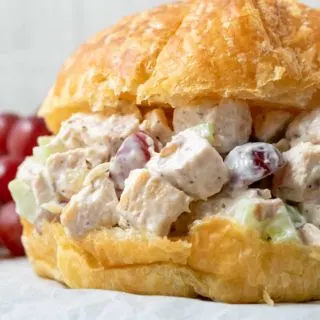 Chicken Salad Croissant with boneless chicken, grapes, almonds, and celery coated in a mayo dressing piled in a large buttery croissant roll.