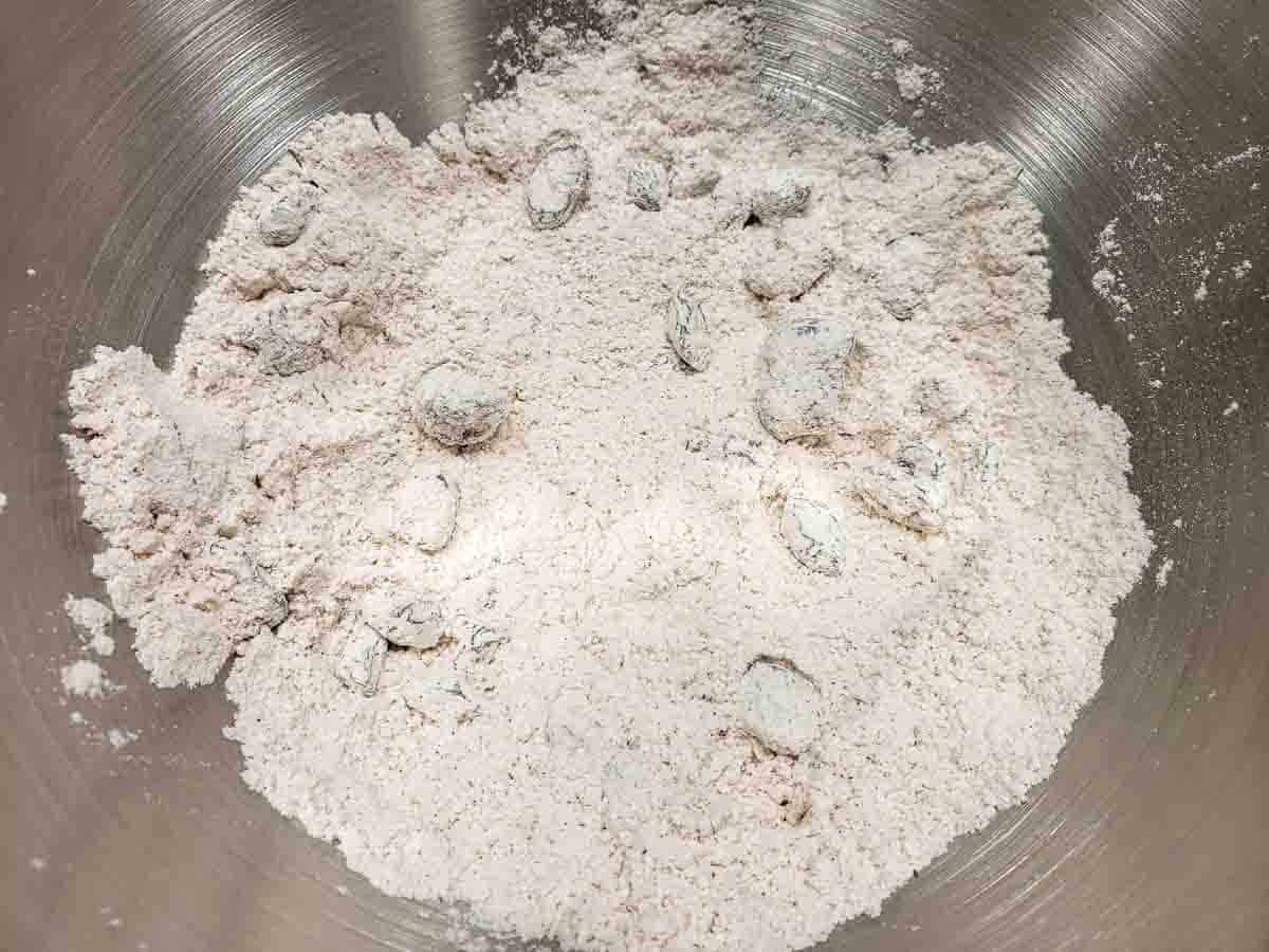 flour, sugar, baking powder, salt, cinnamon, and raisins mixed in a bowl