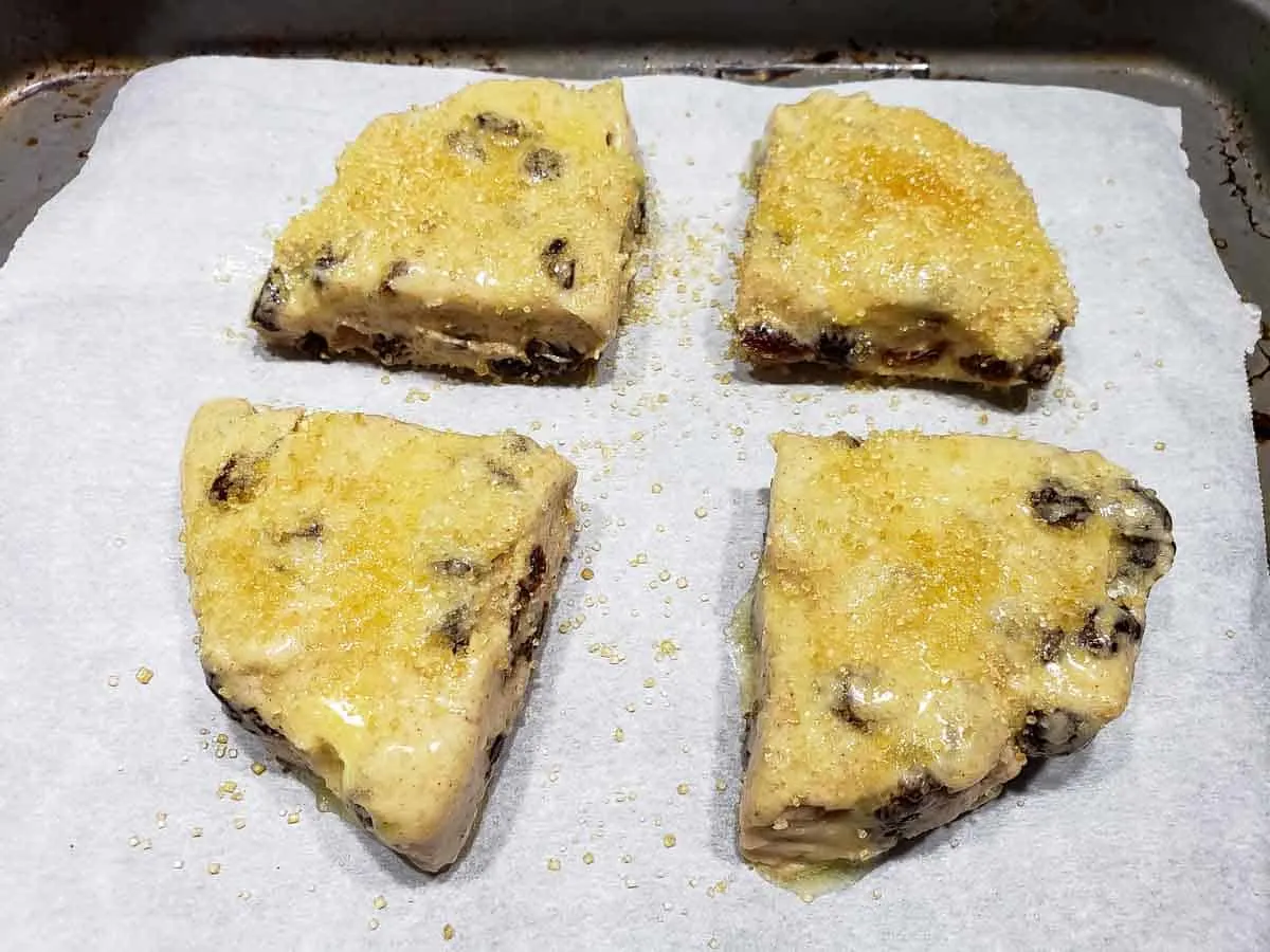 turbinado sugar sprinkled over butter on cinnamon raisin scone dough triangles