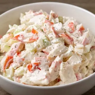 a bowl of crab meat salad with chopped imitation crab meat combined with onion and celery in a creamy mayonnaise dressing.