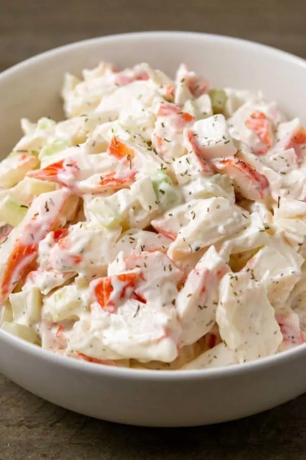 a bowl of small batch seafood salad with chopped imitation crab meat combined with onion and celery in a creamy mayonnaise dressing.