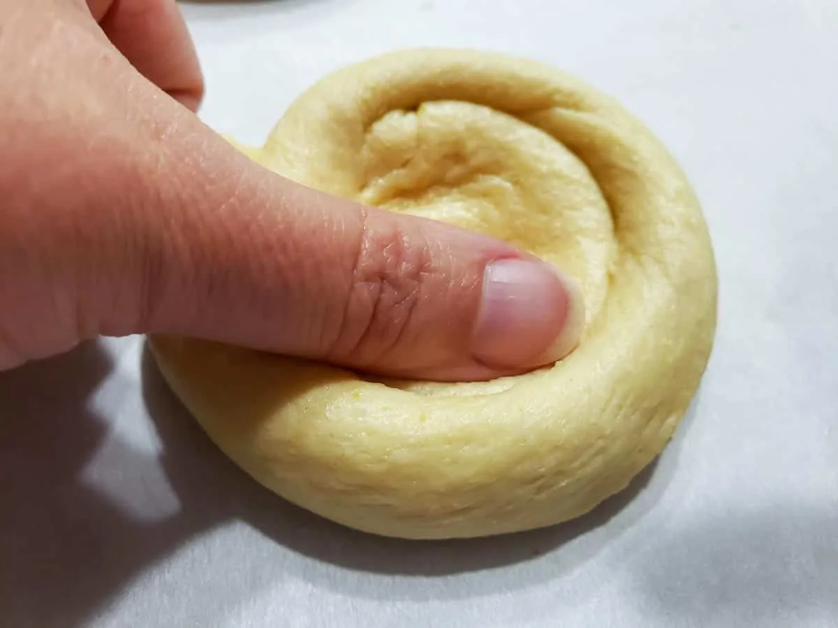 a thumb pressing flat the center of a crescent dough cirle