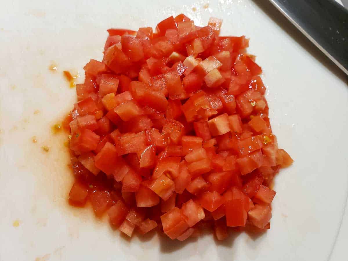diced roma tomatoes on a cutting board.