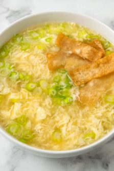 a bowl of egg drop soup topped with crispy wonton croutons.