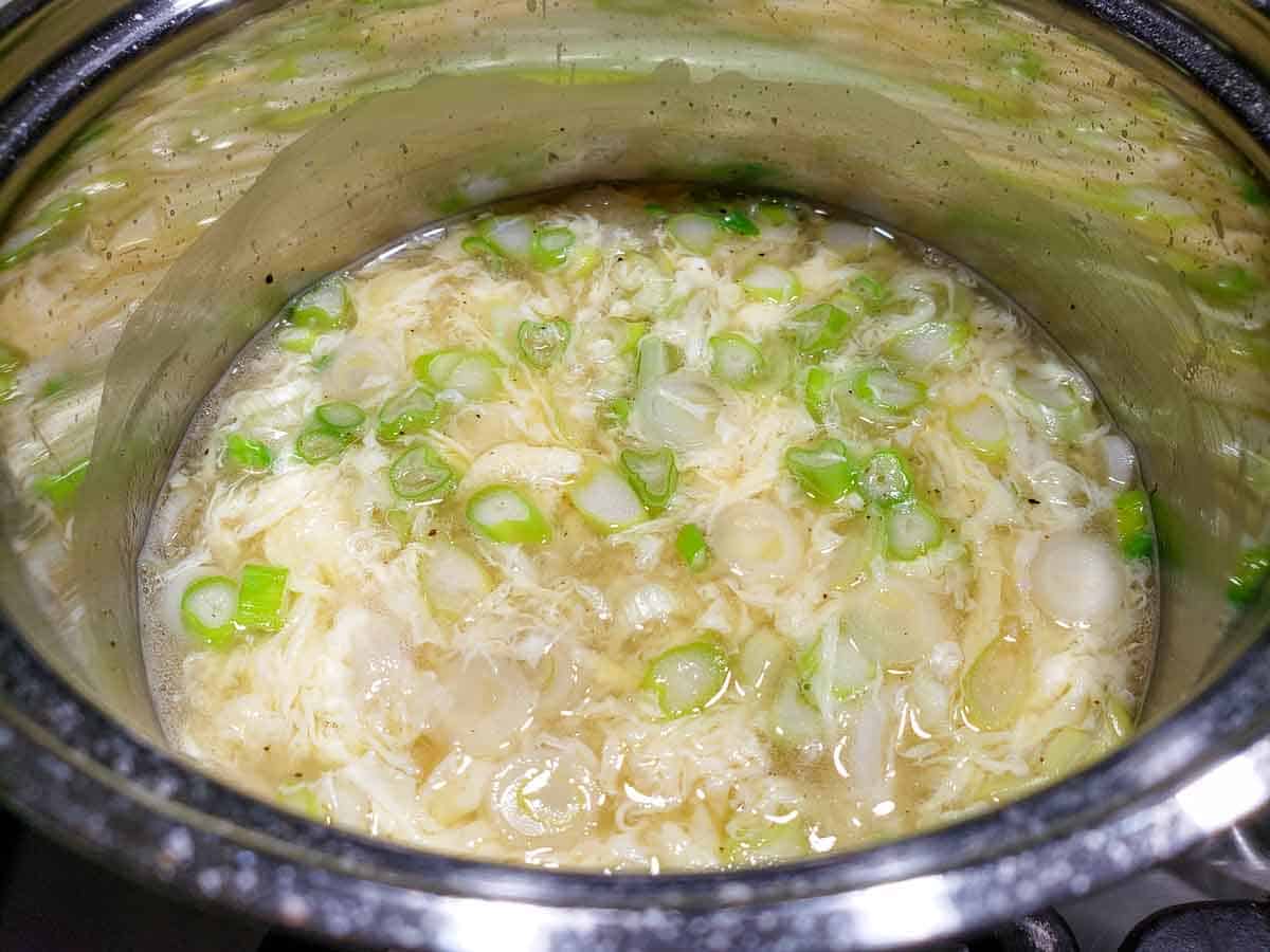 egg drop soup cooking in a sauce pan.