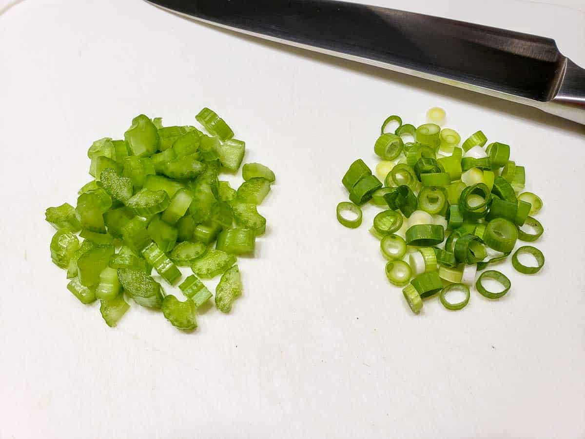 diced celery and green onion on a cutting board.