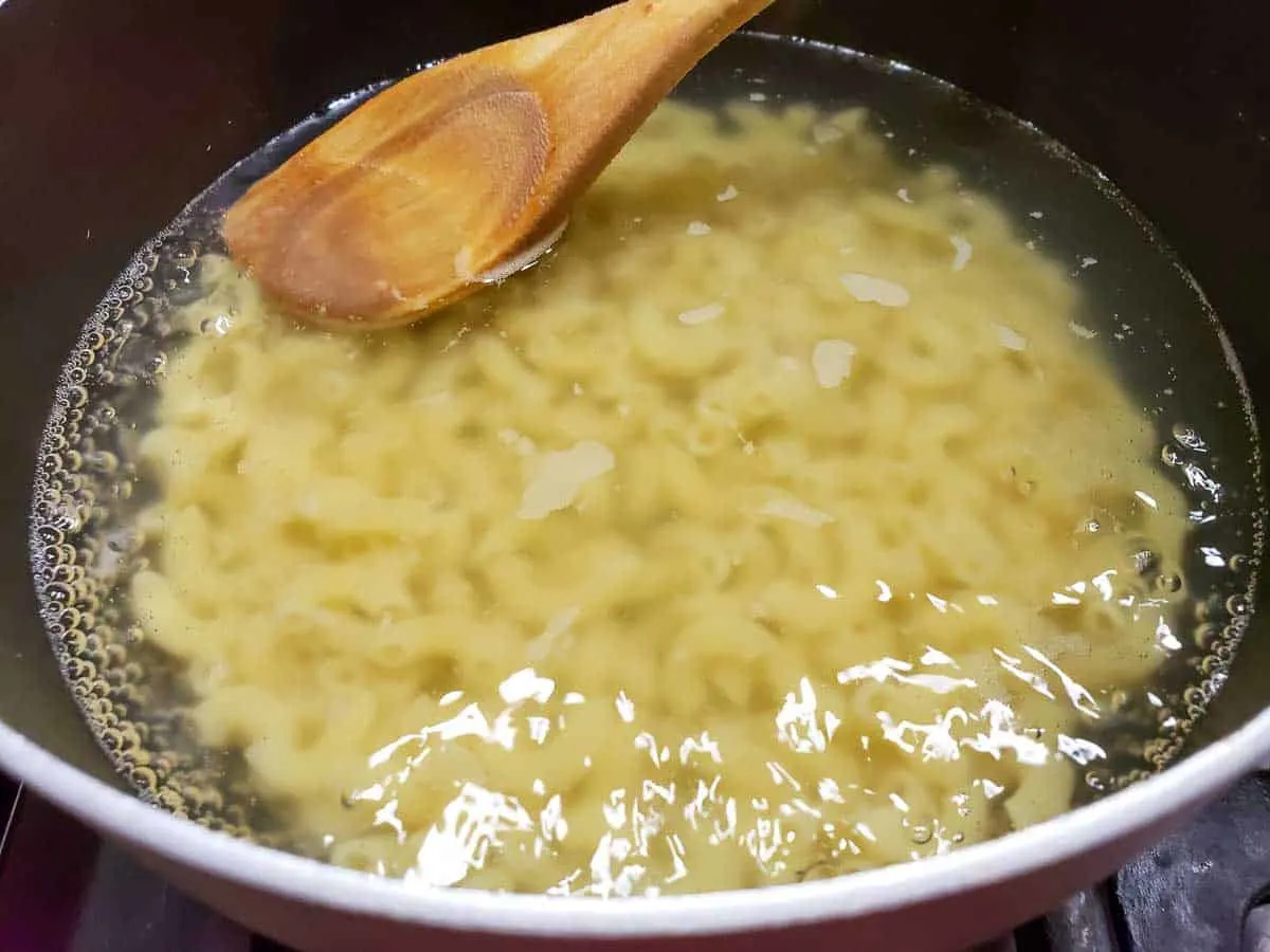 a sauce pan filled with elbow macaroni cooking in boiling water.