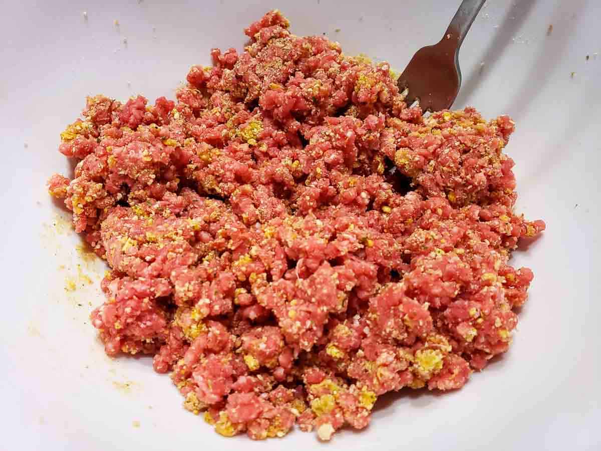 ground beef, fine bread crumbs, and seasonings mixed in a bowl.