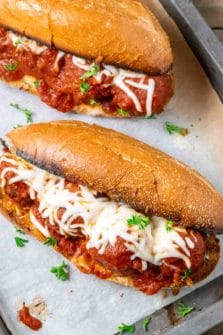 two homemade meatball subs on a baking sheet.